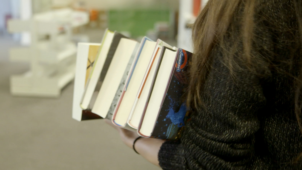 Marianne carrying stack of books